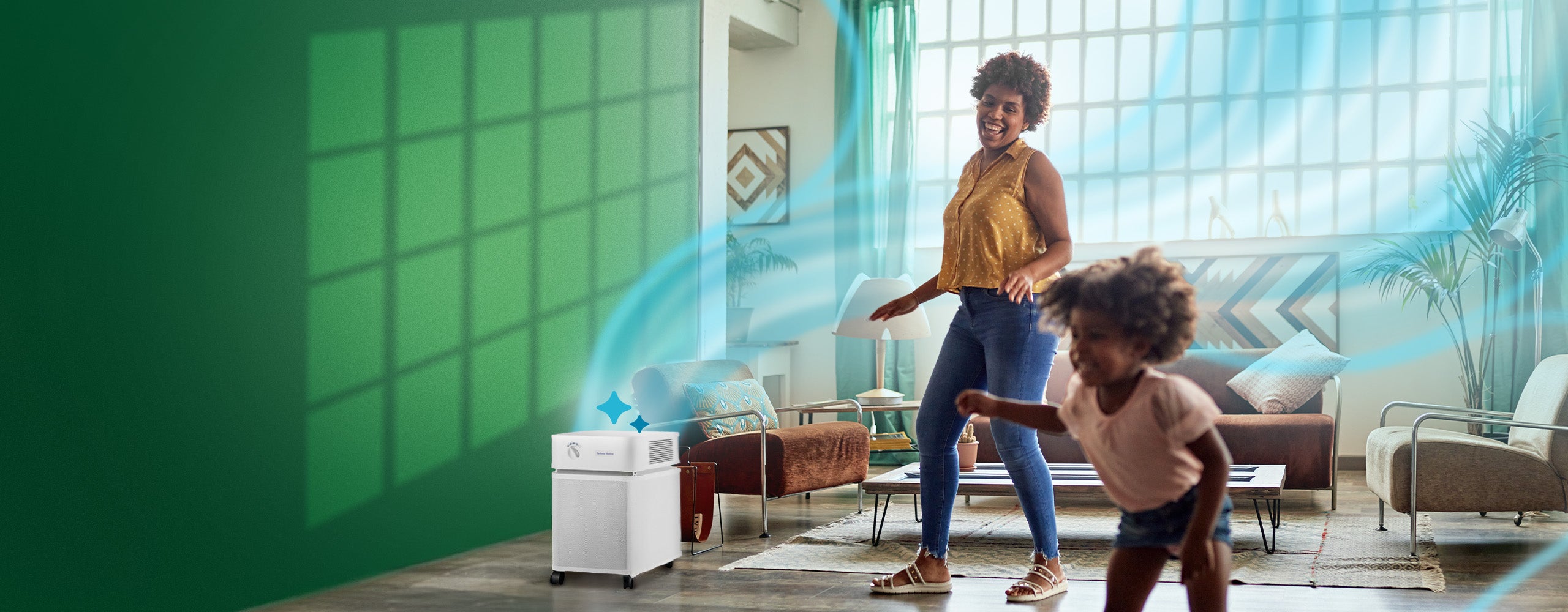 Woman and child playing in a modern living room with green walls and large windows, an air purifier sits in the corner with blue wavy air lines emanating from it