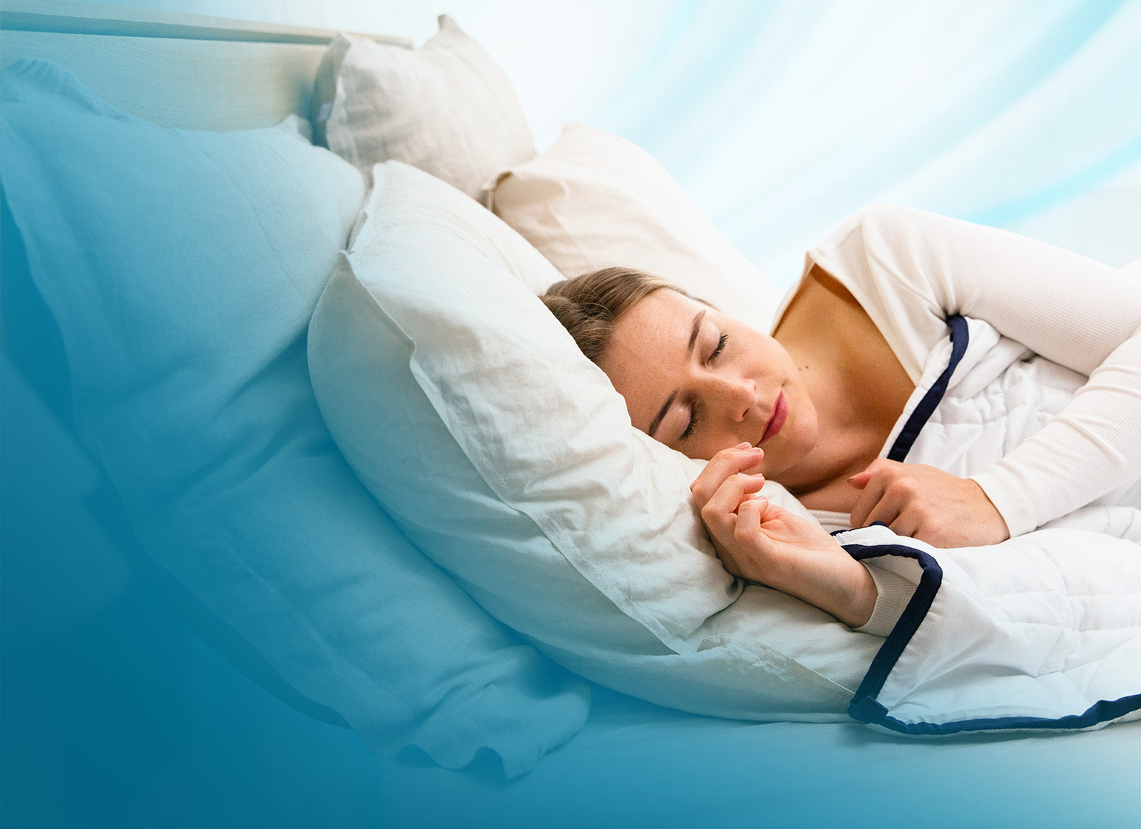 Woman sleeping in a bed with white bedding and blue sheets.