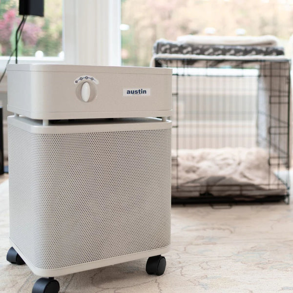 White air purifier on a light wooden floor in front of a dog crate