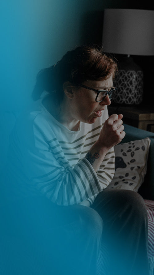 Person sitting on a couch coughing with asthma with a blue overlay