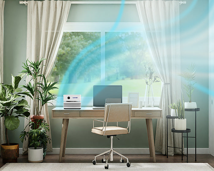 Modern home office with a desk, chair, and decorative plants. Blue air lines emanate from an air purifier. 
