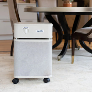 Air purifier with 'austin' branding on a carpeted floor in a room with furniture.