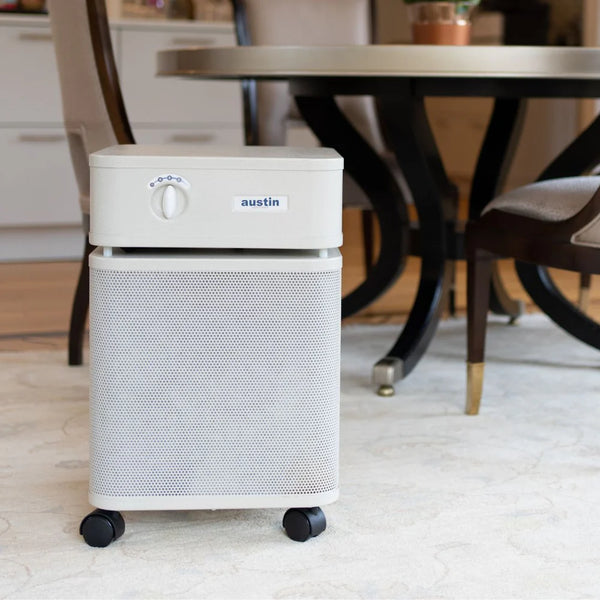 Air purifier with 'austin' branding on a carpeted floor in a room with furniture.