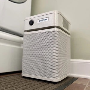 White air purifier with 'austin' branding on a carpeted floor.