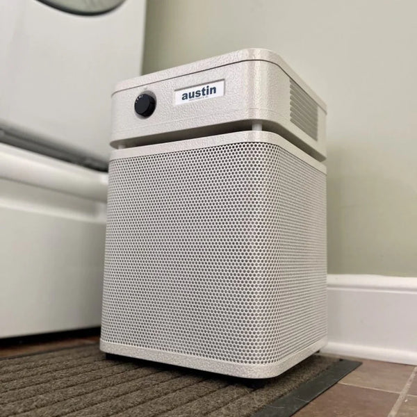 White air purifier with 'austin' branding on a carpeted floor.