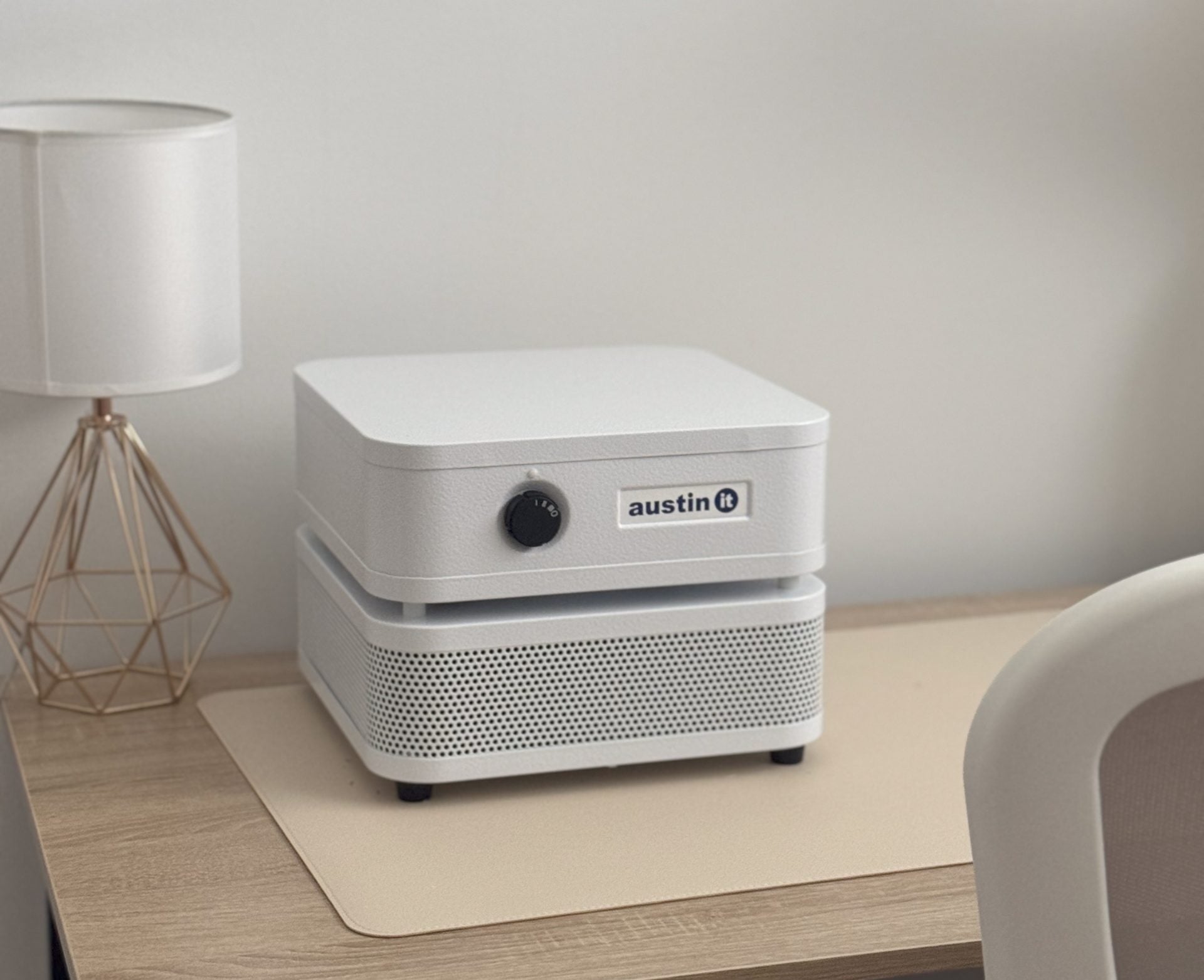 White Austin It air purifier on a wooden desk next to a lamp.