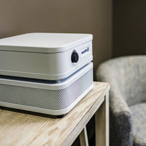 Close up of air purifier on a wooden table with a blurred chair in the background