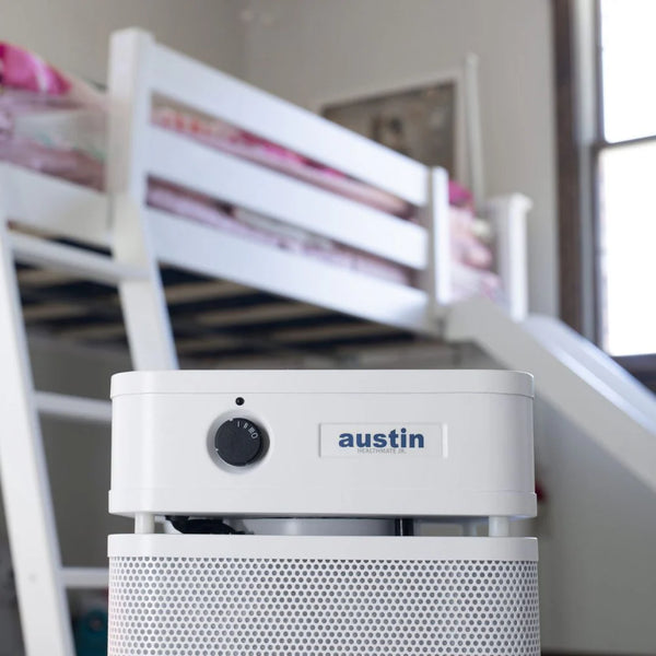 White air purifier with 'austin' branding on a blurred background of a room with bunk beds.