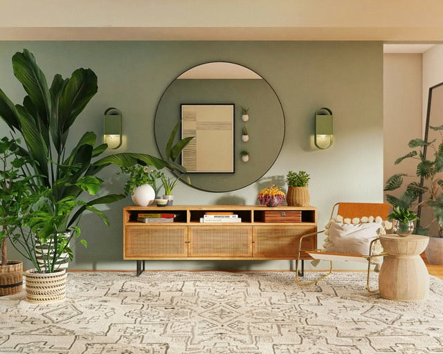Modern living room with wooden furniture, round mirror, and decorative plants.
